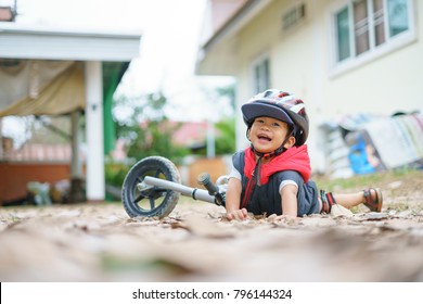 Asian Boy About 2 Years Is Riding Baby Balance Bike And Fall, Get Up On His Own, Playing And Learning Concept