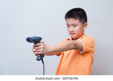 Asian Boy Aim A Fake Gun Made With Barcode Scanner, Studio Shot, On Gray Wall Background With Soft Shadow