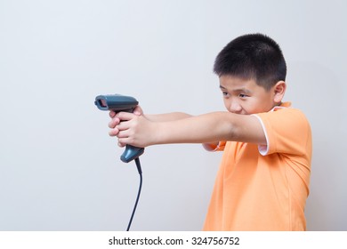 Asian Boy Aim A Fake Gun Made With Barcode Scanner, Studio Shot, On Gray Wall Background With Soft Shadow