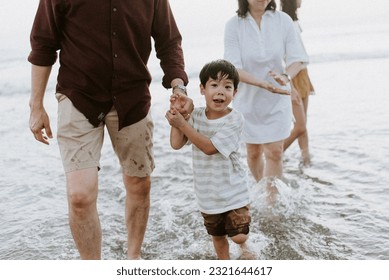 Asian Boy at the Beach Holding Hands with Parents Smiling and Splashing  - Powered by Shutterstock