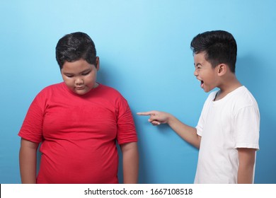 Asian Boy Bullying Mocking Other Boy, Fat Boy Get Bullied At School, Against Blue Background