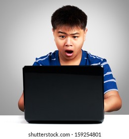 Asian boy at the computer surprised