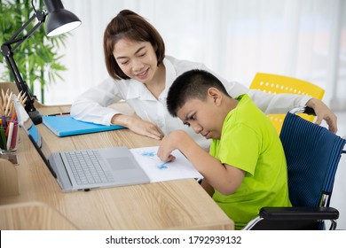 Asian boy with disability in wheelchair drawing picture with Laptop and mother at home. Supportive, Care, Coexistence and education.