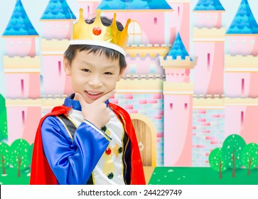 Asian boy is dressed in suit of a prince standing in front of castle