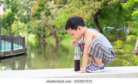 An Asian Boy Drinking Soft Drink Soda On Bottle , Excessive Consumption Of Sugar By Child Under The Age Of 10 Years.
