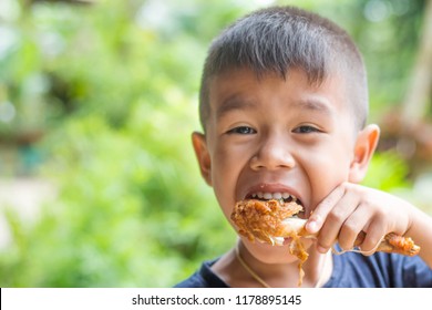 Asian Boy Eating Chicken/child Eating A Chicken Leg