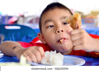 Asian Boy Eating Chicken/child Eating A Chicken Leg 