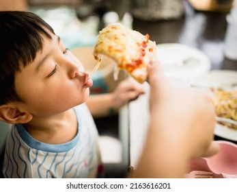 Asian boy eating pizza deliciously by pulling out the pizza by mouth.
 - Powered by Shutterstock