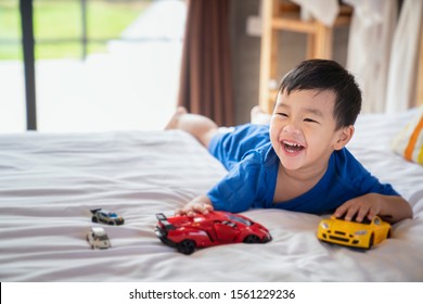 Asian Boy Fun And Play A Car Toy On The Bed, This Image Can Use For Child, Kid And Home Concept