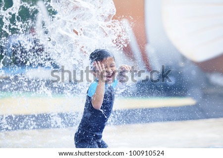 Asian boy having fun with pool fountain shot during summer time