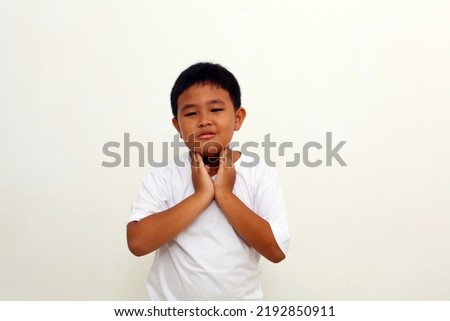Asian boy having sore throat and touching his neck. Isolated on white background