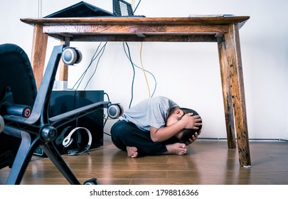 Asian Boy Hiding Under Table Because Of Earthquake.