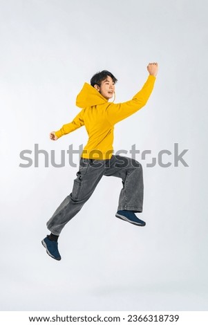 Asian boy jumping in a studio with a white background.