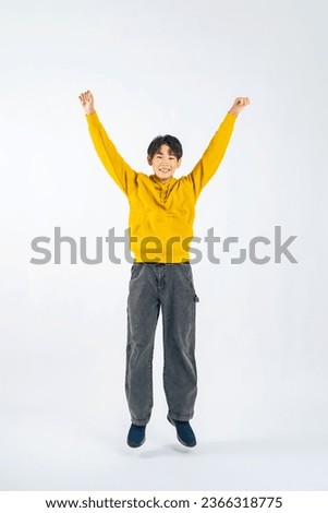 Asian boy jumping in a studio with a white background.