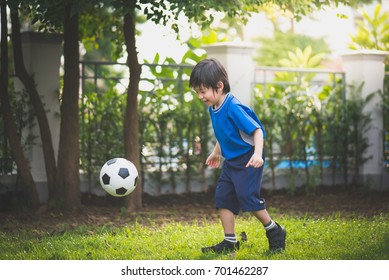 Asian Boy Kicking Football In The Park