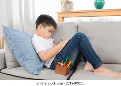 Asian Boy Learning To Use Color Pen And Write On Notebook, He Feel Fun And Happy To Do Home Work, He Stay On Sofa