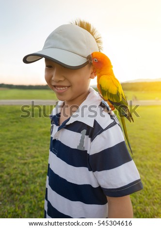 Asian boy play with his pet parrot in the park.