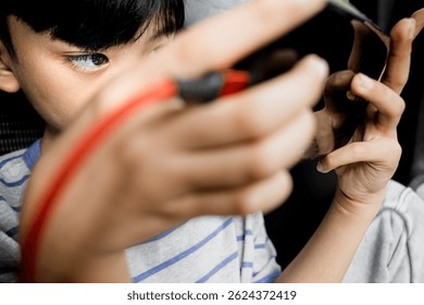 Asian boy playing online game on smartphone while being charged in full concentration inside of a car