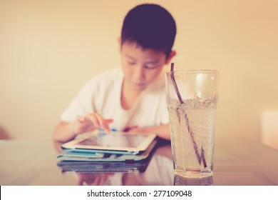Asian boy playing table on table with cool drink. Selective focus at glass.