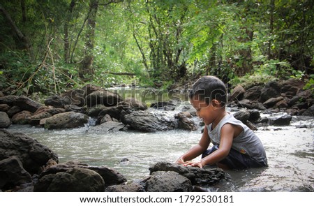 Asian boy playing in waterfall.