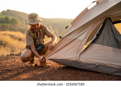 Asian Boy Scouts attending Scout camp pitching their tents in a Boy Scout camp on a mountain near sunset. - Shutterstock ID 2256967183