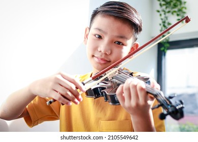 An Asian Boy Sits At Home In The Morning Playing Music. He Was Happily Playing The Violin Of A Classical Instrument. Classical Music Concepts, Develop Learning, Study And Practice In Childhood.