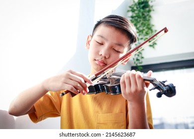 An Asian Boy Sits At Home In The Morning Playing Music. He Was Happily Playing The Violin Of A Classical Instrument. Classical Music Concepts, Develop Learning, Study And Practice In Childhood.