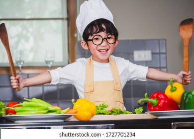 Asian Boy son cooking salad food holdind wooden spoon with vegetable holding tomatoes and carrots, bell peppers on plate for happy family cook food enjoyment lifestyle kitchen in home - Powered by Shutterstock