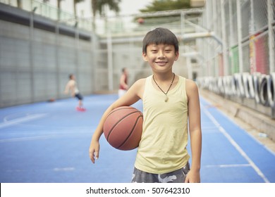 Asian Boy Standing At Basketball Court Smiling