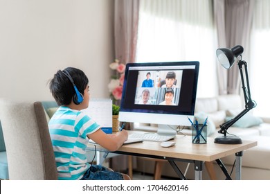 Asian Boy Student Video Conference E-learning With Teacher And Classmates On Computer In Living Room At Home. Homeschooling And Distance Learning ,online ,education And Internet.