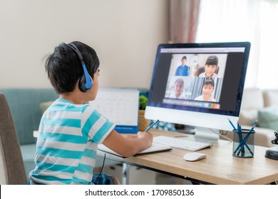Asian boy student video conference e-learning with teacher and classmates on computer in living room at home. Homeschooling and distance learning ,online ,education and internet.