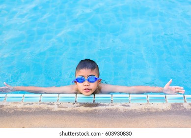 Asian Boy Swimming In The Outdoor Public Pool.Portrait Of Swimming Child With Goggles After Training In Water Pool.