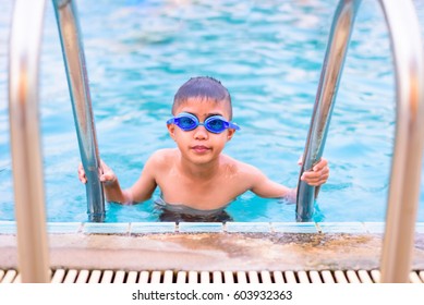 Asian Boy Swimming In The Outdoor Public Pool.Portrait Of Swimming Child With Goggle After Training In Water Pool.