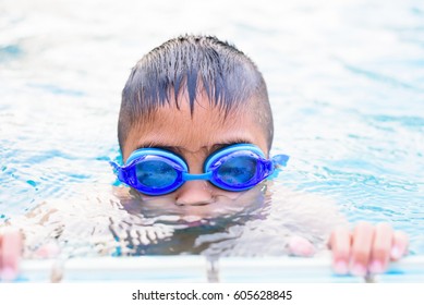 Asian Boy Swimming In The Outdoor Public Pool.Portrait Of Swimming Child With Goggles After Training In Water Pool.