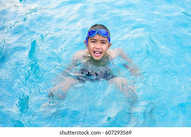 Asian Boy Swimming In The Outdoor Public Pool.Portrait Of Swimming Child With Goggles After Training In Water Pool.