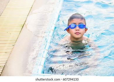 Asian Boy Swimming In The Outdoor Public Pool.Portrait Of Swimming Child With Goggles After Training In Water Pool.