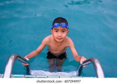 Asian Boy Swimming In The Outdoor Public Pool.Portrait Of Swimming Child With Goggles After Training In Water Pool.