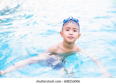 Asian Boy Swimming In The Outdoor Public Pool.Portrait Of Swimming Child With Goggles After Training In Water Pool.