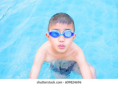 Asian Boy Swimming In The Outdoor Public Pool.Portrait Of Swimming Child With Goggles After Training In Water Pool.