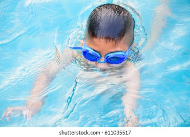 Asian Boy Swimming In The Outdoor Public Pool.Portrait Of Swimming Child With Goggles After Training In Water Pool.