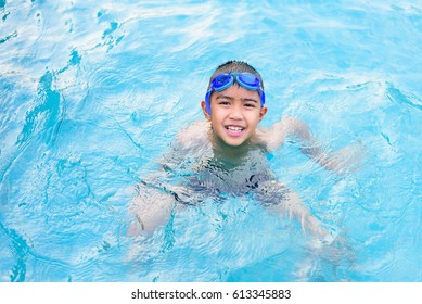 Asian Boy Swimming In The Outdoor Public Pool.Portrait Of Swimming Child With Goggles After Training In Water Pool.