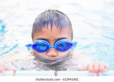 Asian Boy Swimming In The Outdoor Public Pool.Portrait Of Swimming Child With Goggles After Training In Water Pool.