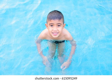 Asian Boy Swimming In The Outdoor Public Pool.Portrait Of Swimming Child With Goggles After Training In Water Pool.