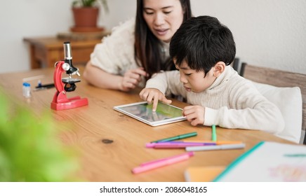 Asian boy using digital tablet indoor - Mother and child using technology to study at home - Powered by Shutterstock