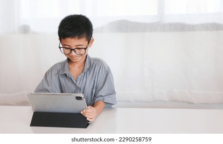 Asian boy using a tablet to learn Things in the wide world that he is interested in by searching for information with a technology network.