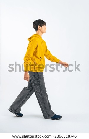 Asian boy walking in a studio with a white background.