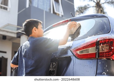 Asian boy washing a car buy rubbing car windows using sponge and soap foam - Powered by Shutterstock