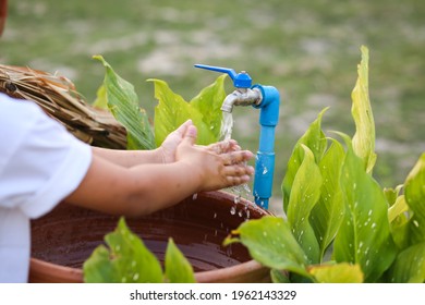 An Asian boy washing his hand at an outdoor faucet sink and water tab. - Shutterstock ID 1962143329
