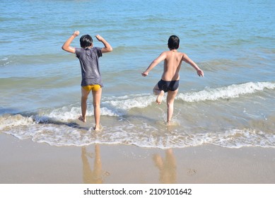 Asiatische Jungen laufen fröhlich zusammen ins Meer.
