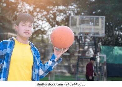 Asian boys in plaid shirt holding and playing basket ball with friends at outdoor basketball court of his school, soft focus, concept for freestyle and lifestyle of young teens around the world. - Powered by Shutterstock